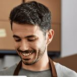 Smiling man wearing a brown apron.