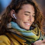 Smiling woman with earphones and scarf.